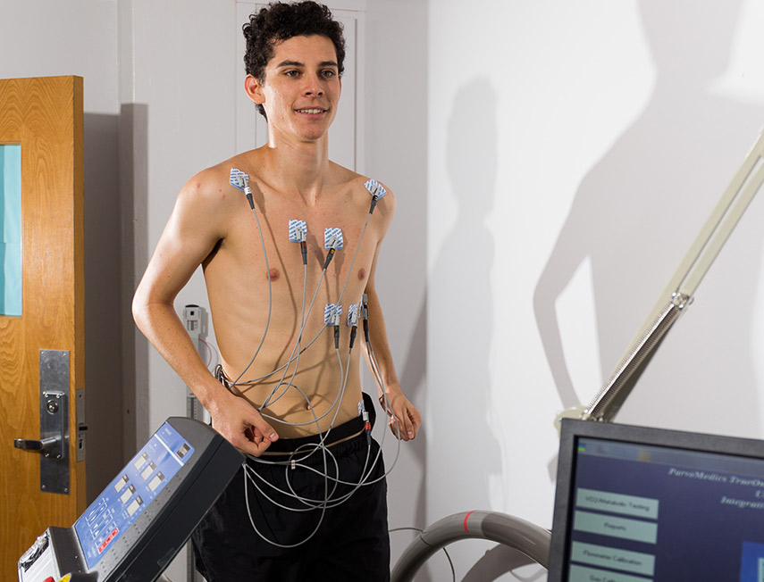 A young man on a treadmill with electrodes measuring his heart activity