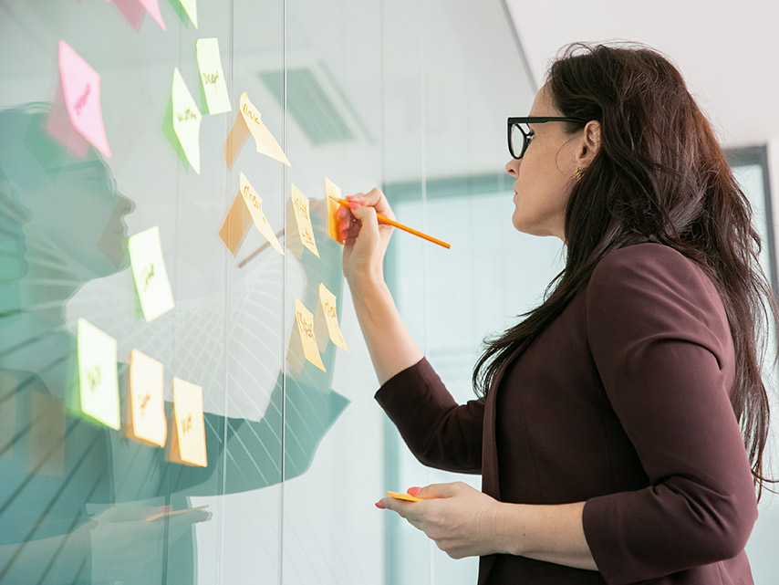 a faculty member with post it notes on a board in a planning session