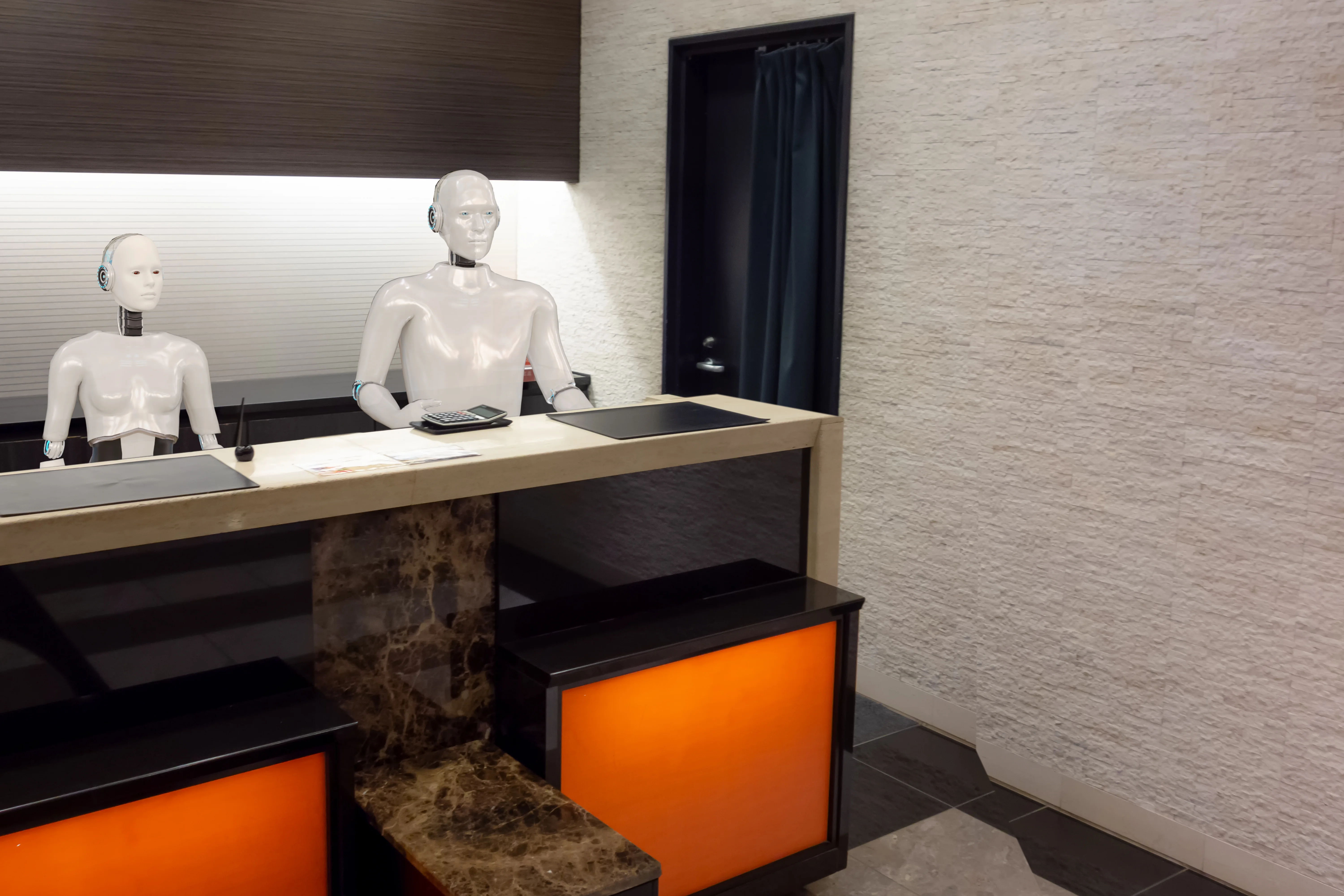 Two robots behind a receptions desk at a hotel