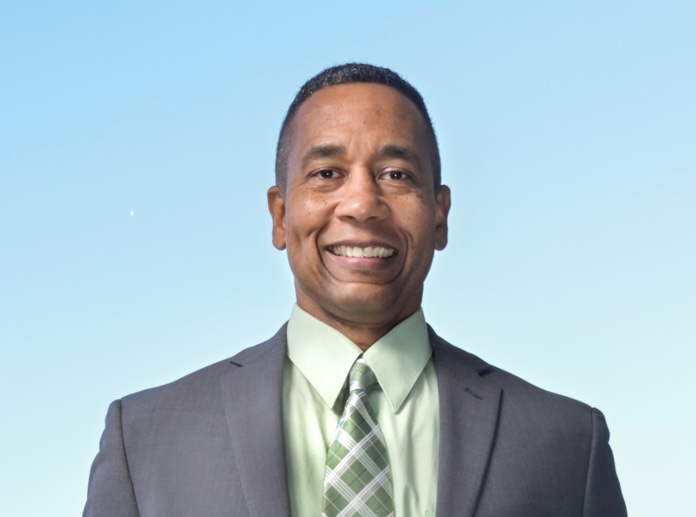 head and shoulders shot of a man with short dark hair in a suit and tie.