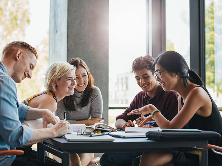 Five students assembled around a table discussing AI initiatives